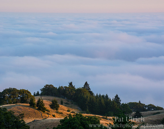 Illuminated hillsides above the fog
